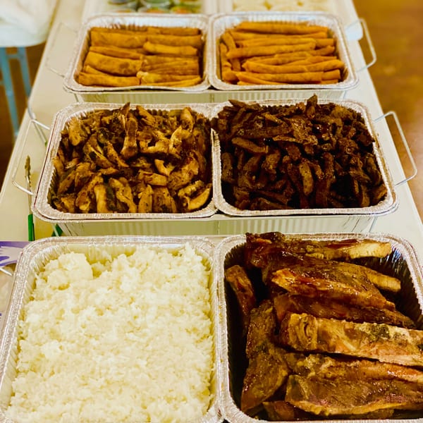 Toa's Ohana Hawaiian catering spread with ribs, chicken, rice, and sweet potato fries in foil trays.