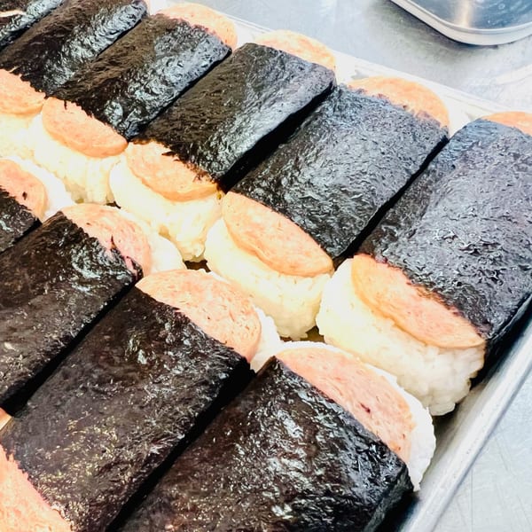A tray filled with rows of Toa's Ohana Hawaiian Restaurant's Spam Musubi, featuring grilled Spam on rice wrapped in nori.
